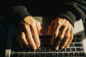 hands on laptop keyboard typing, The Instagram photo was taken with polaroid camera by his friend. He is wearing black hoodie. his hair is short, he is a large middle-aged man . top view. The image was captured at day, with a candid, grainy film filter --ar 16:9 --v 7 Job ID: 8c5ddfb8-7d09-4cc4-ac31-3c0db67c6c39
